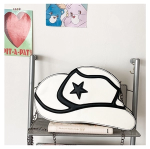 Detail of white cowboy hat shaped crossbody bag with black star and metal chain strap