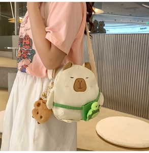 Détail du sac à bandoulière capybara blanc avec breloques tortue et peluche marron
