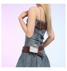 Silver mini crossbody bag with crocodile pattern and metallic chain strap on model
