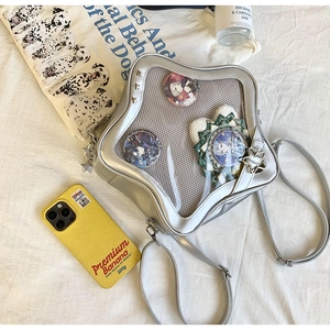 Détail du sac ita argenté avec fenêtre en étoile et badges sur fond en tissu texturé