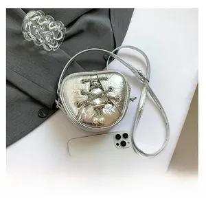 Détails de ce mini sac cœur argenté avec lacets croisés et accents de perles
