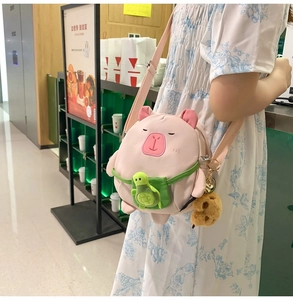 Détail du sac bandoulière cochon rose avec poche tortue verte et pendentif en peluche