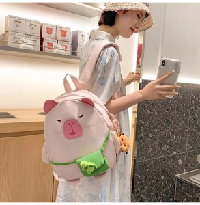 Detailed view of pink capybara backpack featuring a green mini bag and turtle pendant
