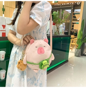 Détail du sac à bandoulière peluche capybara rose avec charm tortue sur un mannequin