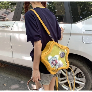 Outdoor shot of a yellow star-shaped ita bag with a clear window showing anime badges
