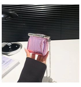 Close-up of pink mini crossbody bag with crocodile texture and silver chain strap