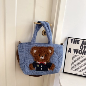 Detailed view of blue gingham quilted bag with a 3D plush bear hanging on a door handle