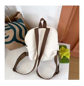Rear view of white canvas toddler backpack featuring adjustable brown shoulder straps