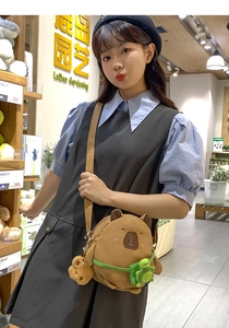 Detail of plush capybara crossbody bag featuring a turtle charm and braided strap