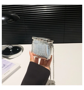 Macro detail of silver crocodile embossed mini bag with retro metal clasp and chain