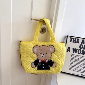 Close-up of yellow quilted nylon crossbody bag with a cute cartoon bear patch detail