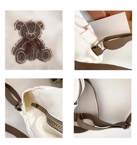 Detail view of cute bear embroidery, canvas texture, and sturdy metal strap buckles