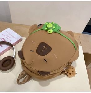Detail view of cute brown bear backpack with turtle plush and cookie keychain