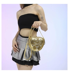 Détail du sac à main doré en forme de cœur avec fini miroir et pendentif perle