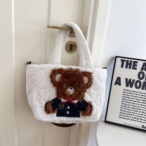Detail of white quilted tote bag featuring a 3D plush bear in denim with red bow