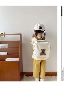 Close-up of cute teddy bear embroidery on a cream canvas toddler backpack with brown straps