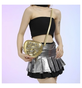 Détail du sac doré en forme de cœur avec breloques perles et design de chaîne croisée