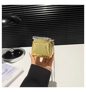 Close-up of gold crocodile-patterned mini bag with silver metal frame and chain strap