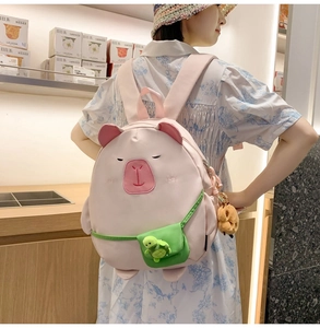 Detail of pink capybara schoolbag with mini green crossbody bag and plush pendant