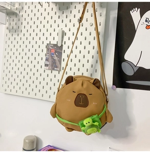 Detail of cute Capybara crossbody bag with turtle charm on a white pegboard