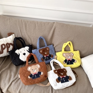 Detail of five quilted crossbody bags with cute animal patches on a soft fabric sofa