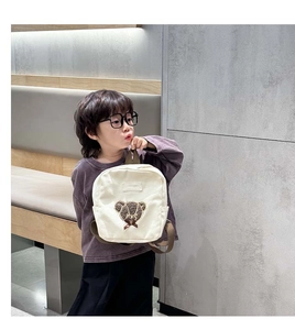 Detail of cute brown bear patch on cream canvas toddler backpack with brown straps