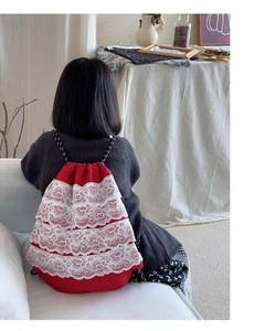 Détail du sac à dos rouge pour enfant avec dentelle blanche multicouche et cordons tissés