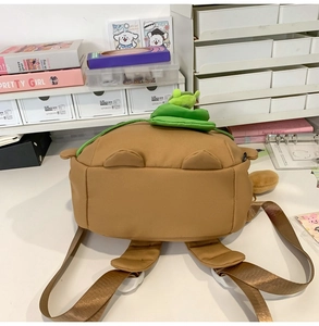 Detail of cute brown capybara backpack featuring a green plush leaf and adjustable straps
