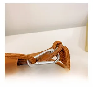 Détail du crochet métallique argenté et de la sangle tissée sur sac enfant brun