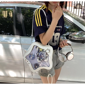 Detailed view of a white star-shaped ita bag featuring a clear heart window with anime pins
