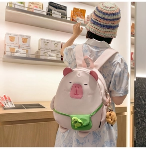 Detail view of pink capybara cartoon backpack with plush charms and embroidered cute features