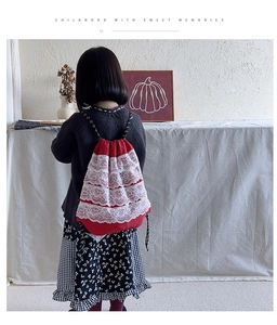 Sac à dos rouge avec cordons et volants en dentelle blanche porté par un enfant