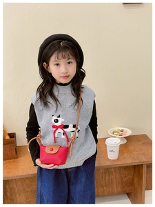 Détail de la petite sacoche rouge pour enfant avec gilet en tricot à motif de vache