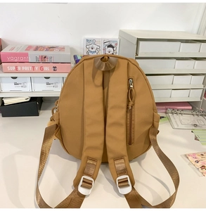 Detail of light brown nylon backpack back showing adjustable straps and anti-theft zip pocket