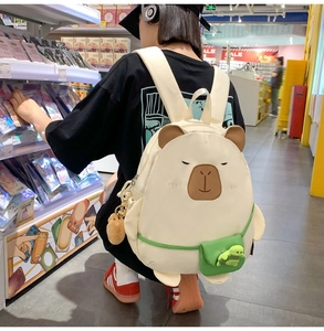 Detail of cute beige cartoon backpack with embroidery, green mini bag, and plush charm
