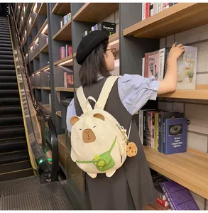 Detail of cute beige capybara backpack with green turtle pocket and plush pendant accessory