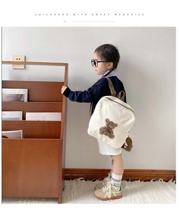 Detail of cute bear embroidery on a cream canvas toddler backpack with brown straps