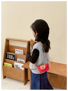 Détail d'un mini sac à bandoulière contrasté porté par un enfant au style épuré