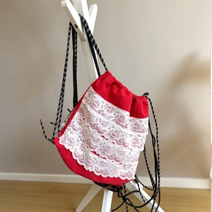 Détail du sac à dos à cordon rouge avec volants en dentelle blanche et motif léopard