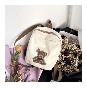 Detailed view of canvas toddler backpack featuring a cute brown bear embroidery and bow