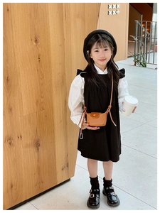 Fille au style français portant un mini sac bandoulière en cuir marron et robe noire