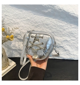 Détail du sac argenté en forme de cœur avec chaînes métalliques et pendentifs en perles