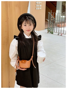 Détail d'une fille portant un mini sac bandoulière en cuir marron avec une boucle aimantée