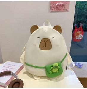 Close-up of cute white plush capybara backpack with green mini bag and turtle charm