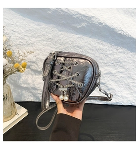 Détail du sac à main argenté en forme de cœur avec chaîne et breloques en perles
