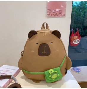 Cute capybara backpack with green turtle accessory on a desk with lifestyle props