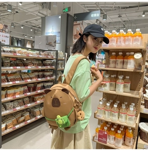 Detail of cute brown plush capybara backpack with green turtle charm and soft texture