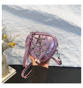 Détail du mini sac rose en forme de cœur avec lacets en chaîne argentée et perles
