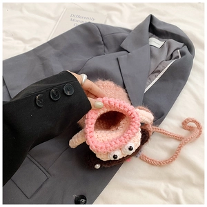 Close-up of pink crochet monster coin purse with cute eyes on a dark grey blazer