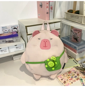 Pink cartoon capybara backpack detail with a cute green turtle mini bag on desk